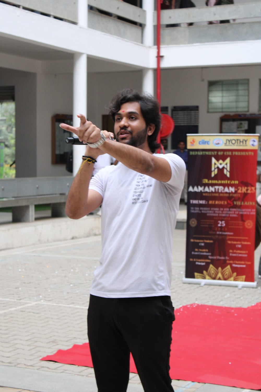 Pointing into the audience in a white tee